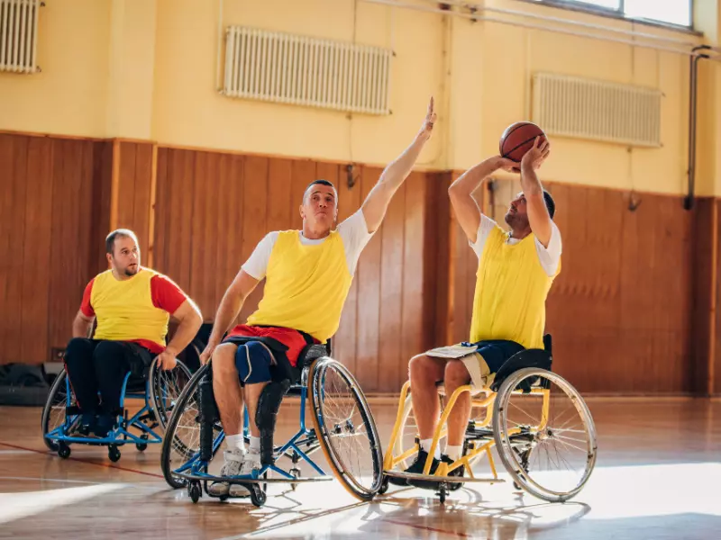 Group of disabled friends in wheelchair playing indoor basketball