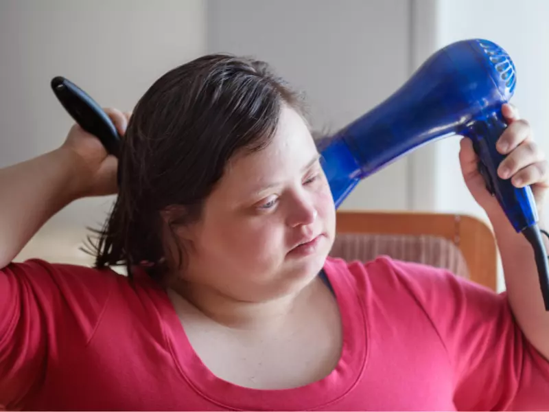 Disabled girl drying hair with hairdryer