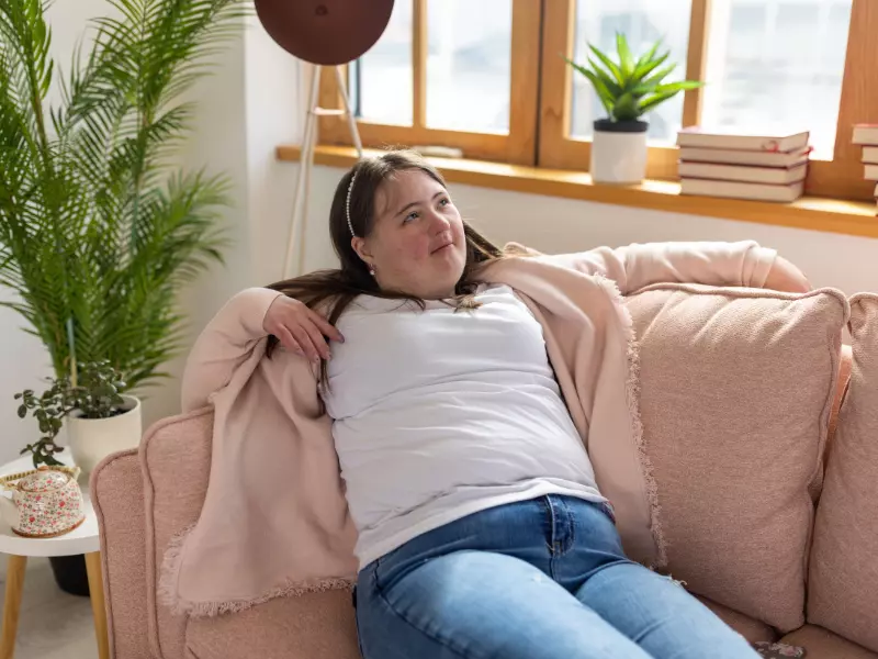 Happy disabled woman sitting on couch and smiling