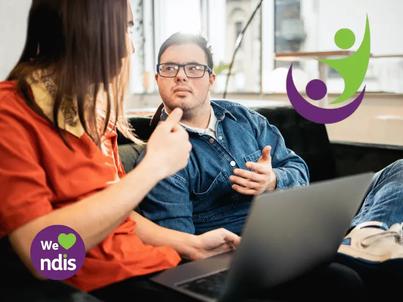 Disabled man with down syndrome sitting on couch with carer chatting